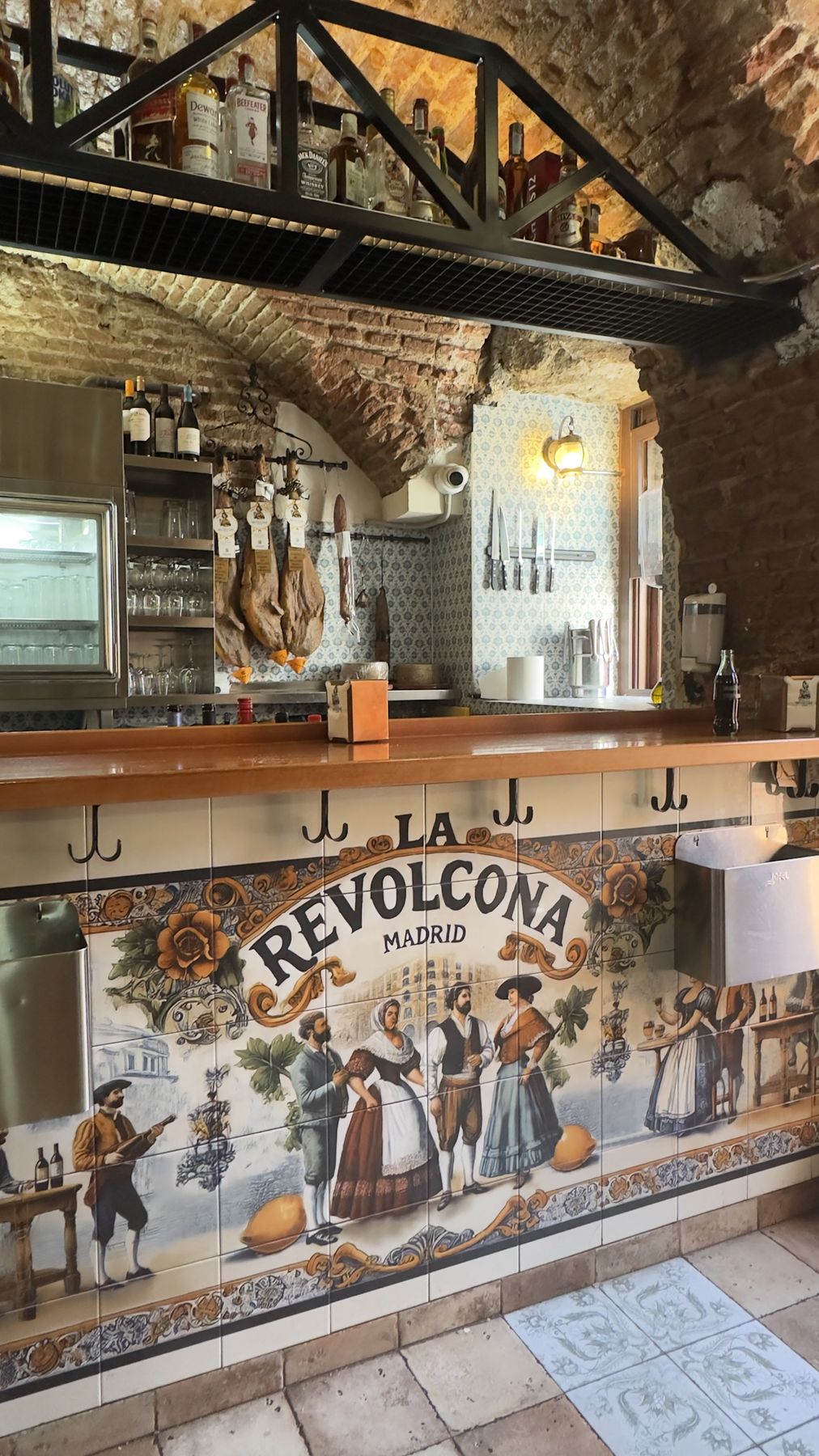 The bar, with hams hanging and the tiled mural